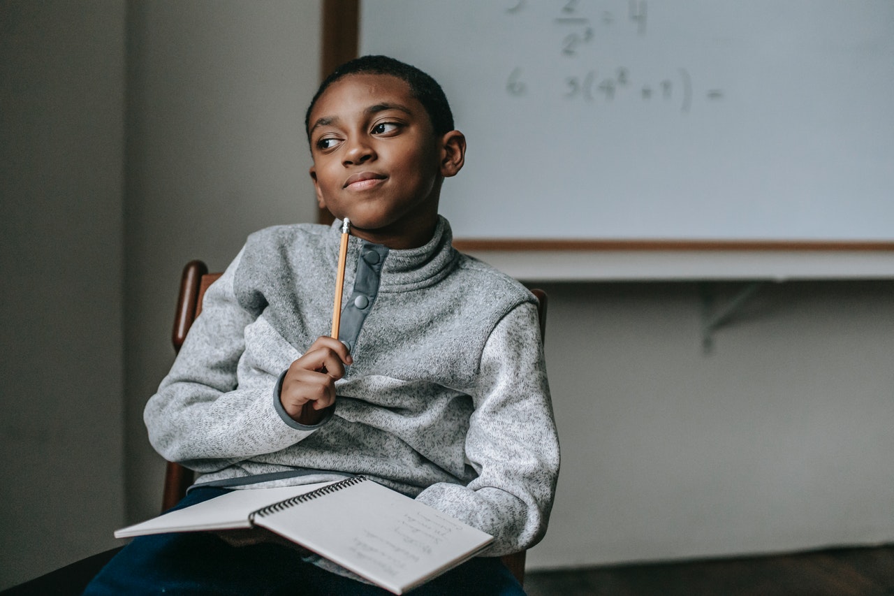 a boy with a book and pencil thinking