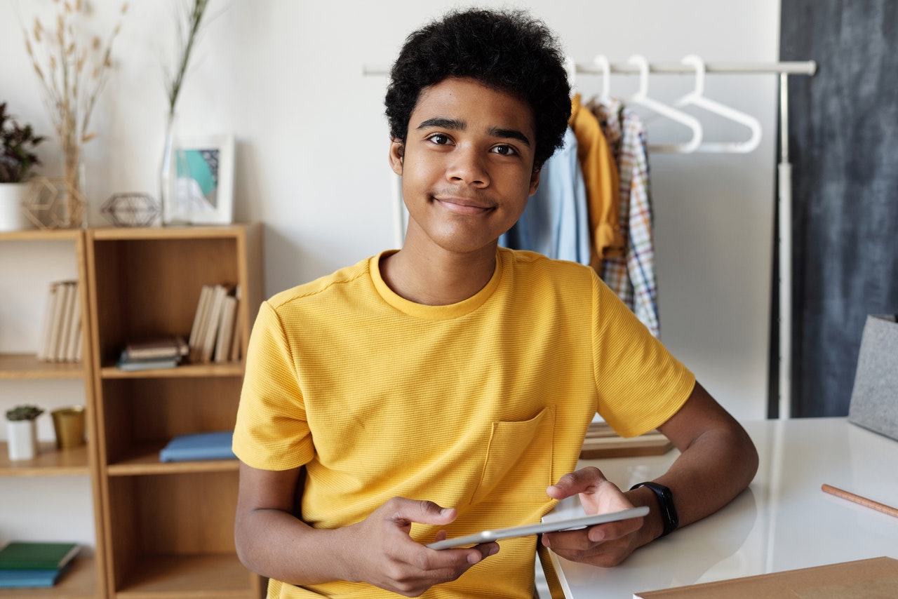 teen in yellow with a tablet in his hands